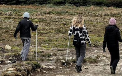 Tourists hiking on Ushuaia Martial Glacier trail with trekking poles.