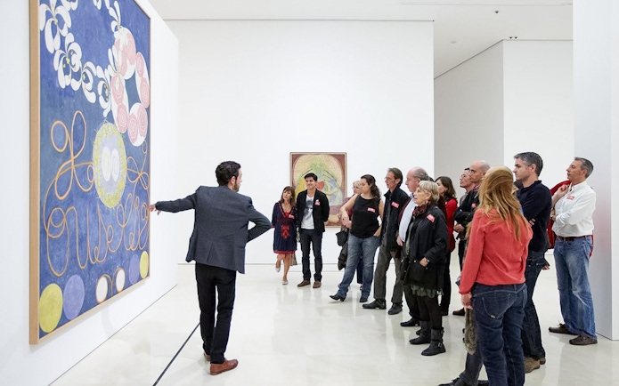 Visitors on a guided tour at Picasso Museum in Malaga, viewing artwork.