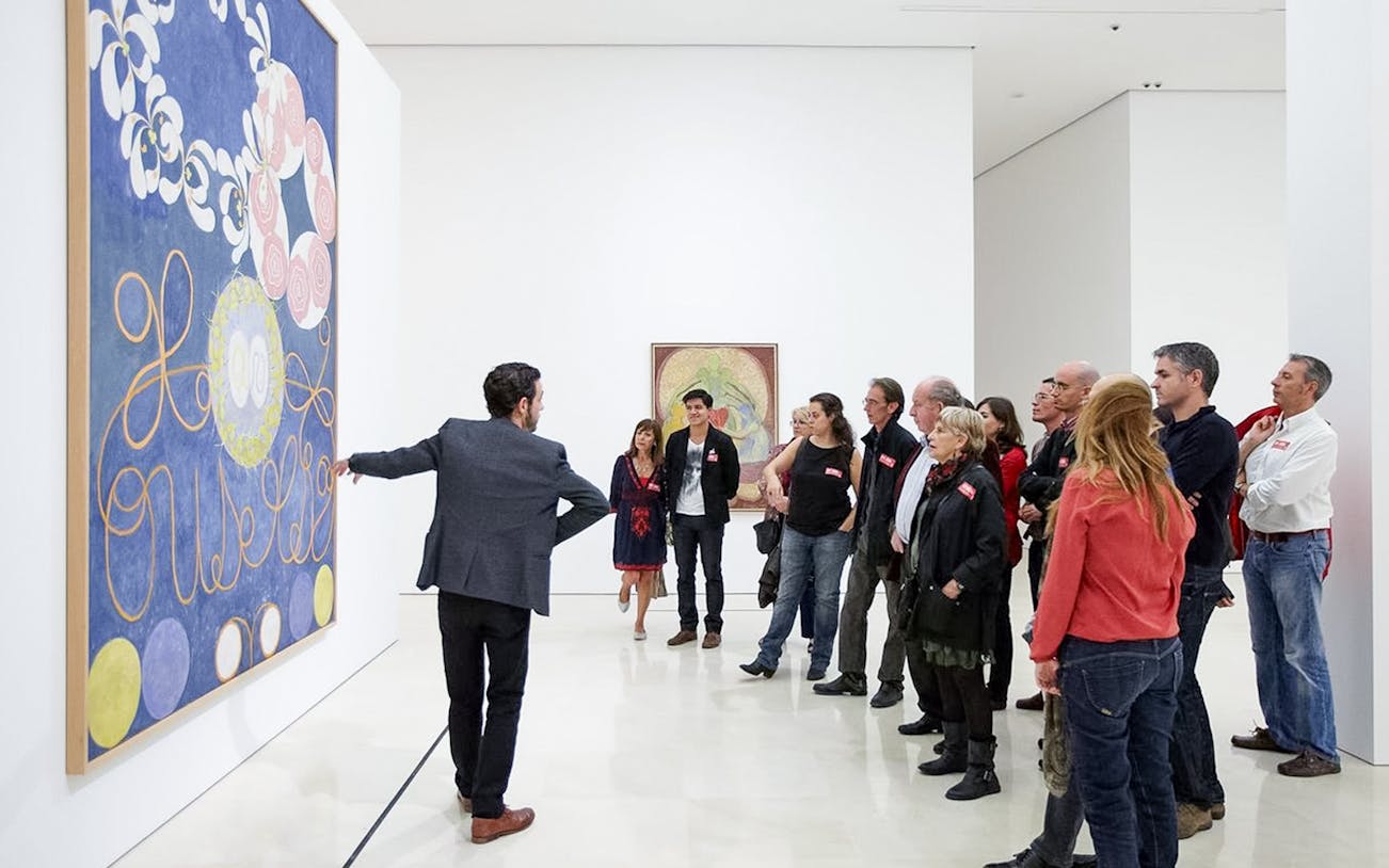 Visitors on a guided tour at Picasso Museum in Malaga, viewing artwork.
