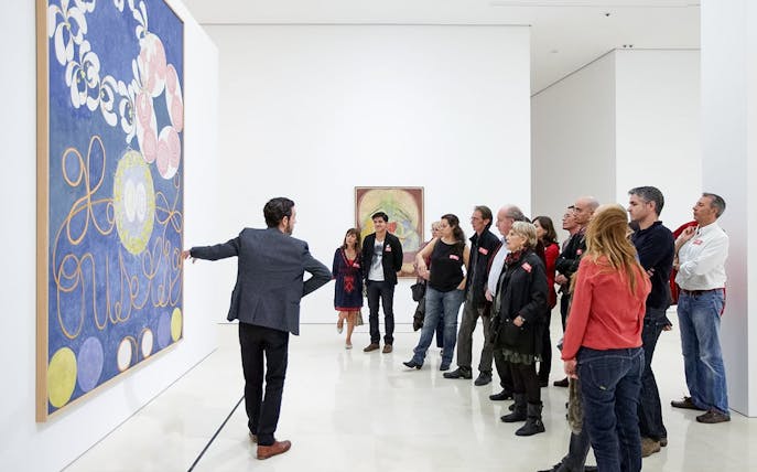 Visitors on a guided tour at Picasso Museum in Malaga, viewing artwork.