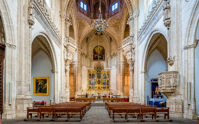 Interior of the Monastery of San Juan de los Reyes, Toledo, Spain, featuring ornate arches and altar.