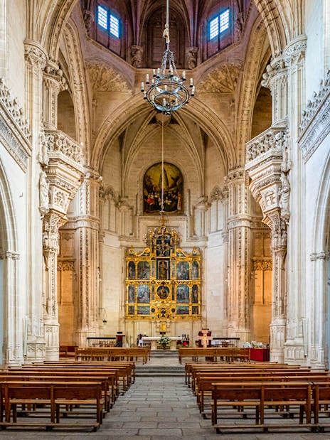 Interior of the Monastery of San Juan de los Reyes, Toledo, Spain, featuring ornate arches and altar.