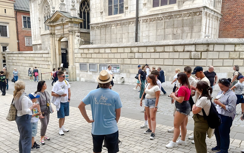 Tour group gathered outside Wawel Cathedral, Krakow, listening to a guide.
