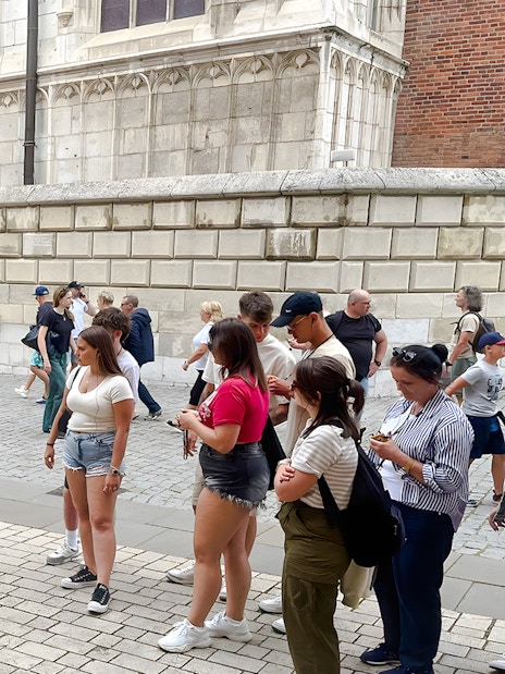 Tour group gathered outside Wawel Cathedral, Krakow, listening to a guide.