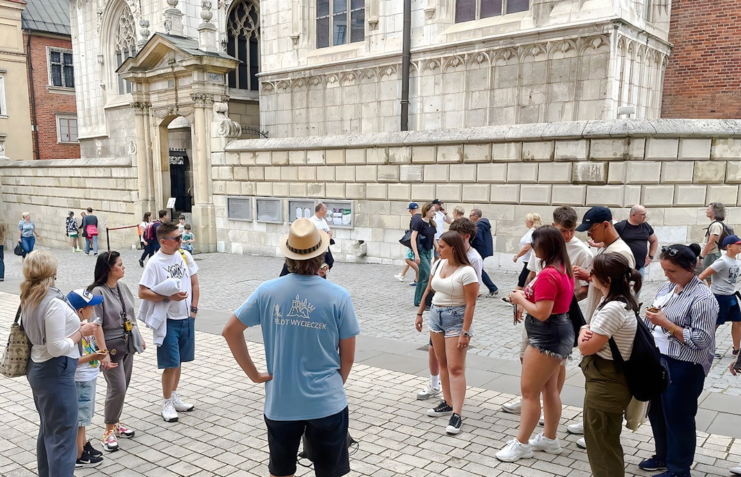 Tour group gathered outside Wawel Cathedral, Krakow, listening to a guide.