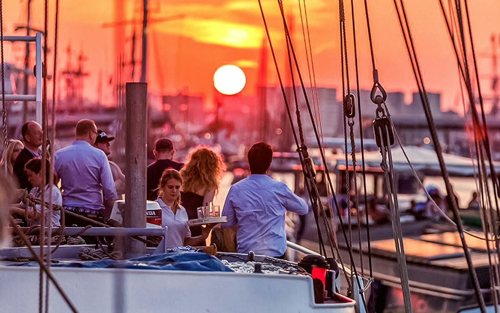 Sunset cruise in Amsterdam with people enjoying an open bar on deck.