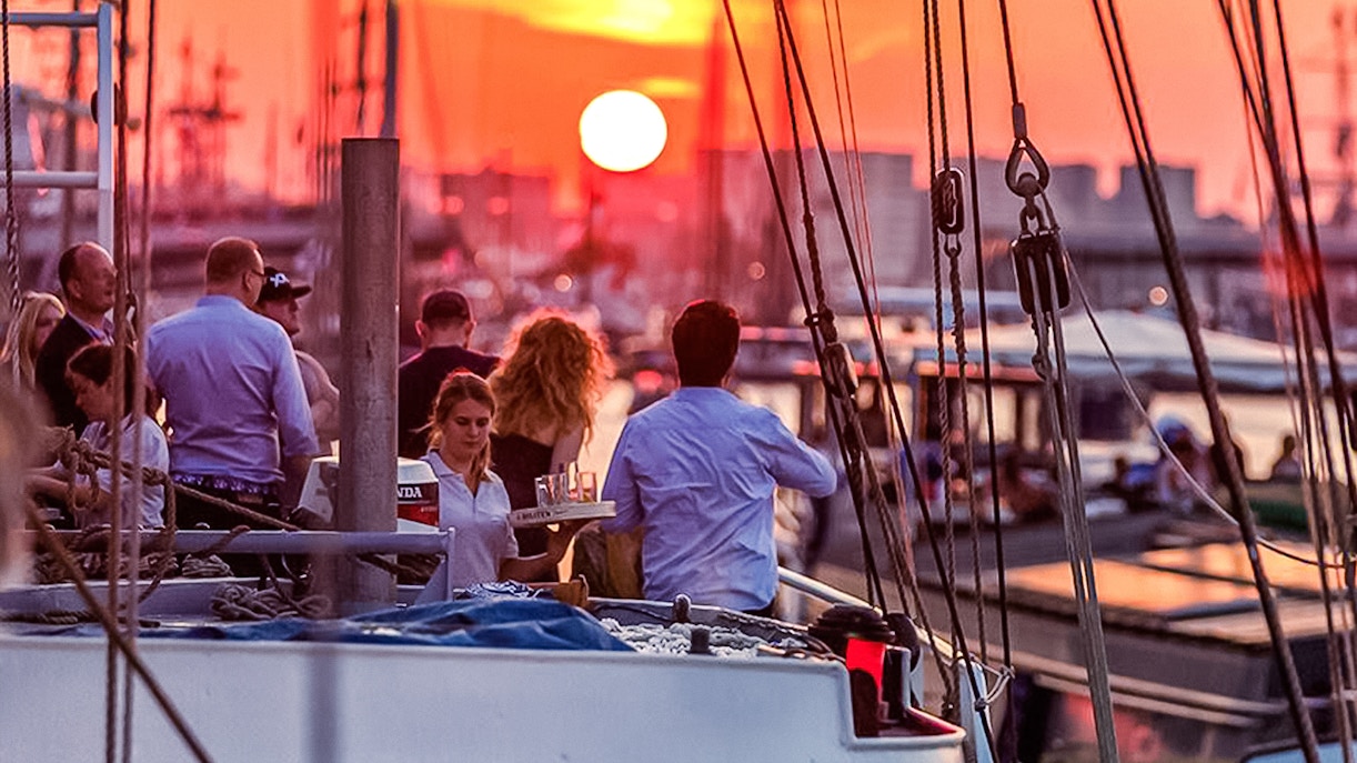 Sunset cruise in Amsterdam with people enjoying an open bar on deck.