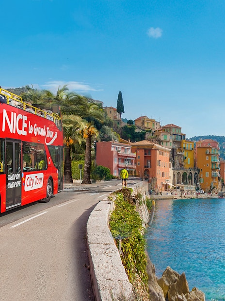 Nice city tour bus on Promenade des Anglais with coastal view.