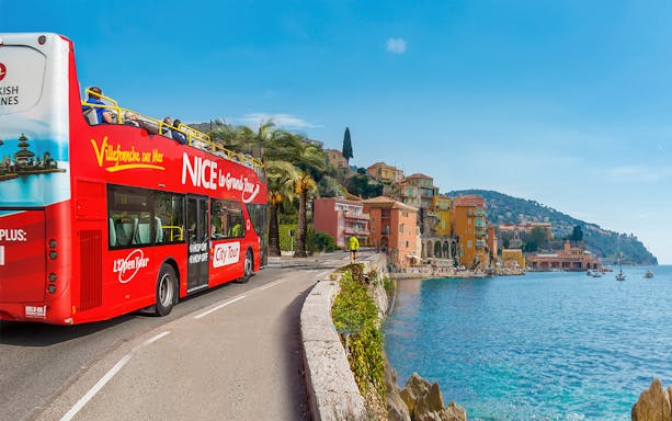 Nice city tour bus on Promenade des Anglais with coastal view.