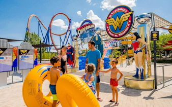 Family at Parque Warner Beach with Superman and Wonder Woman statues.