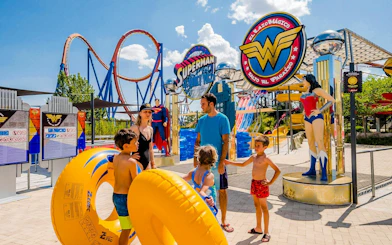 Family at Parque Warner Beach with Superman and Wonder Woman statues.