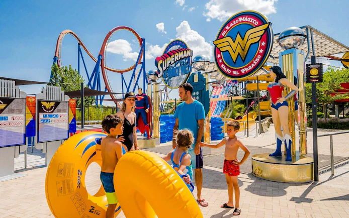 Family at Parque Warner Beach with Superman and Wonder Woman statues.