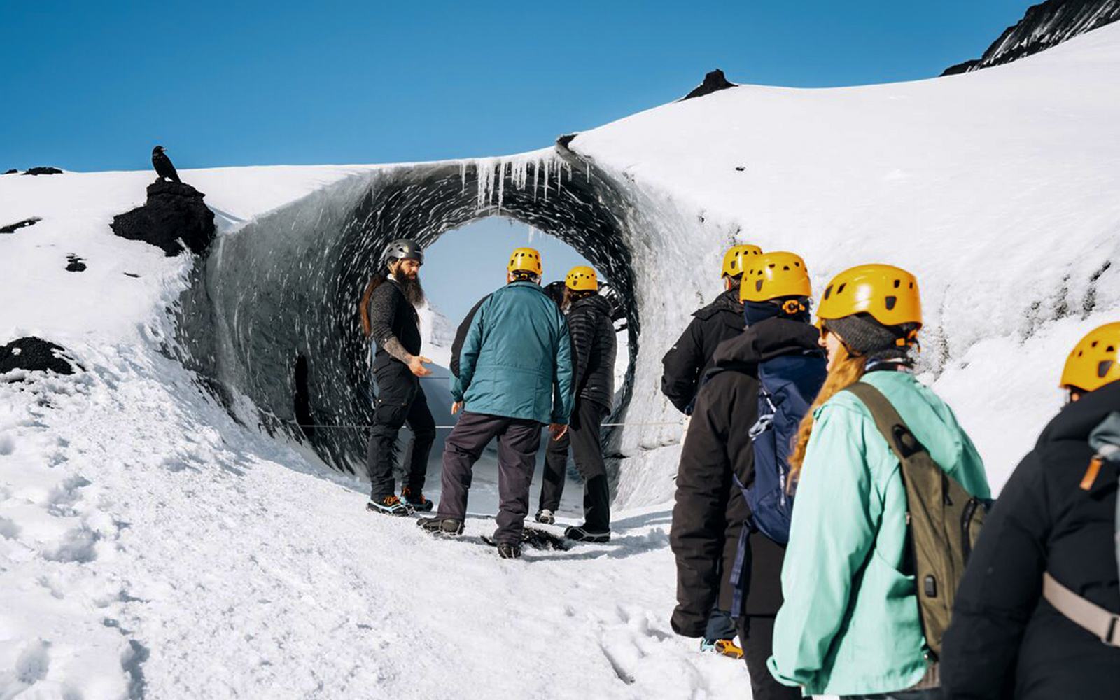 Tour guide assisting group at Katla Ice Cave entrance in Iceland.