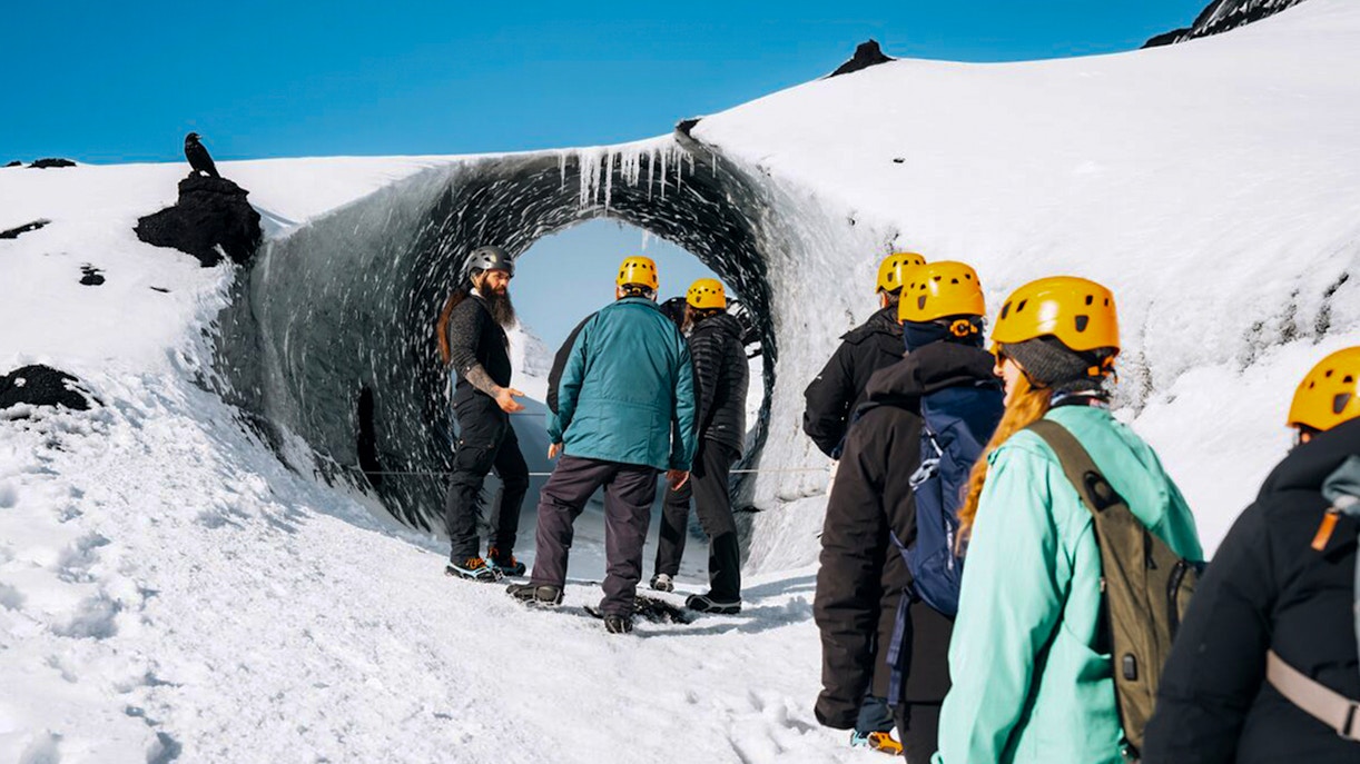 Tour guide assisting group at Katla Ice Cave entrance in Iceland.