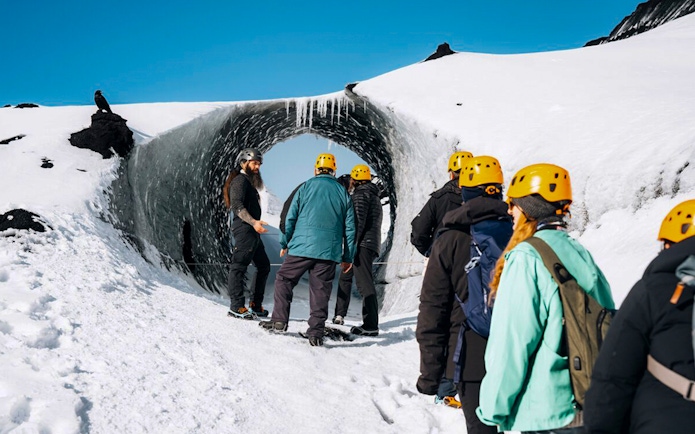 Tour guide assisting group at Katla Ice Cave entrance in Iceland.