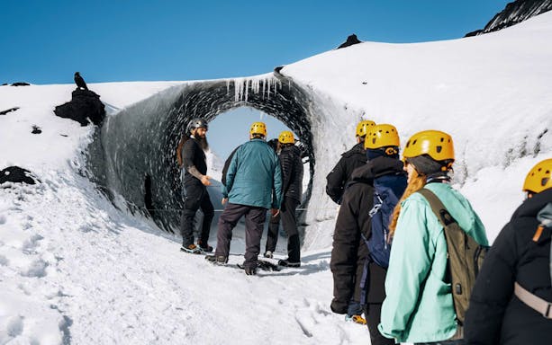 Tour guide assisting group at Katla Ice Cave entrance in Iceland.
