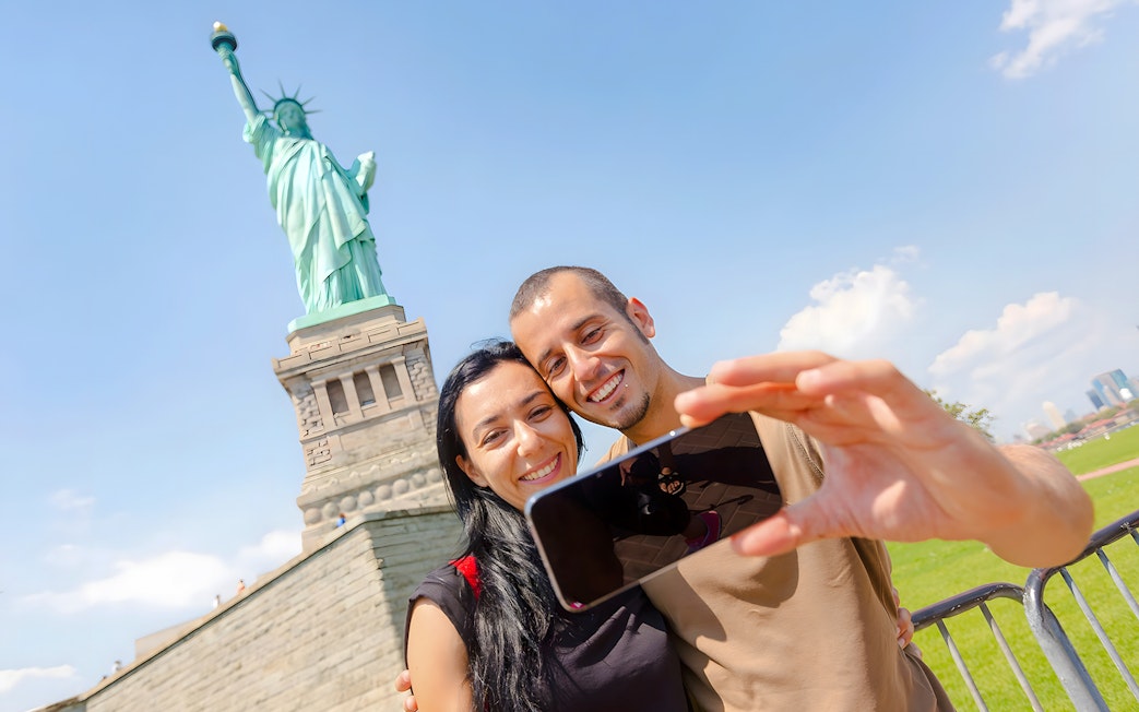 Couple taking selfie at Statue of Liberty, New York City.