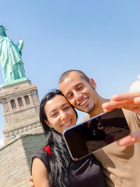Couple taking selfie at Statue of Liberty, New York City.