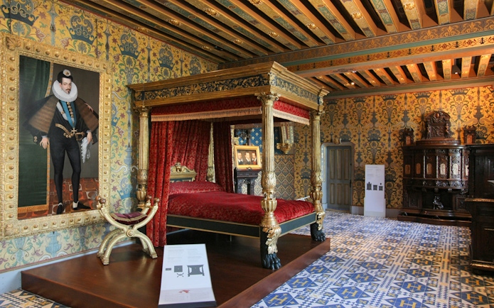 Royal Blois Castle bedroom with ornate canopy bed and historical portrait.