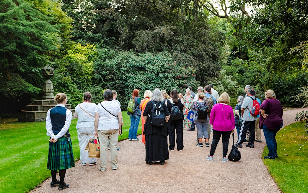 Group of tourists on a guided tour in the gardens of Palace of Holyroodhouse.