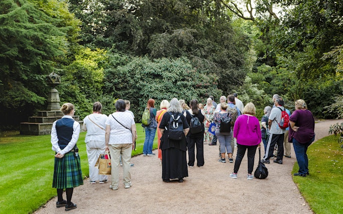 Group of tourists on a guided tour in the gardens of Palace of Holyroodhouse.