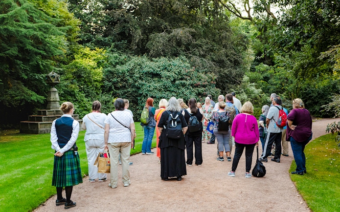 Group of tourists on a guided tour in the gardens of Palace of Holyroodhouse.