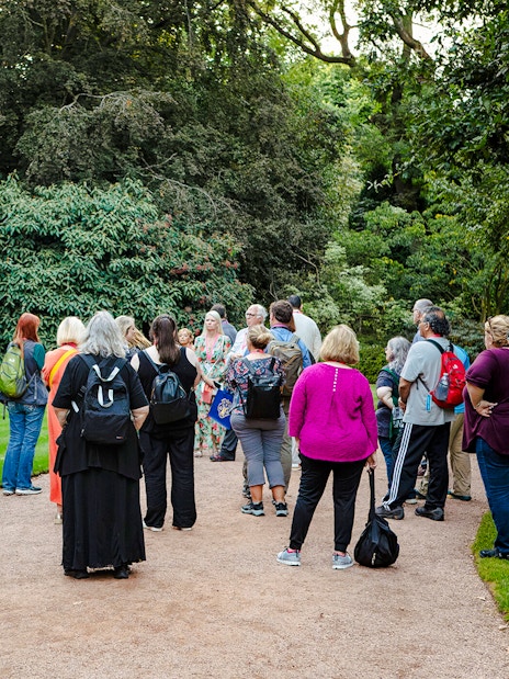 Group of tourists on a guided tour in the gardens of Palace of Holyroodhouse.