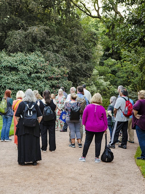 Group of tourists on a guided tour in the gardens of Palace of Holyroodhouse.