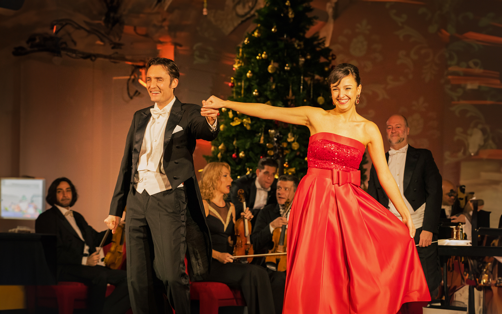 Performers at Schonbrunn Palace Concert with orchestra and festive decor.