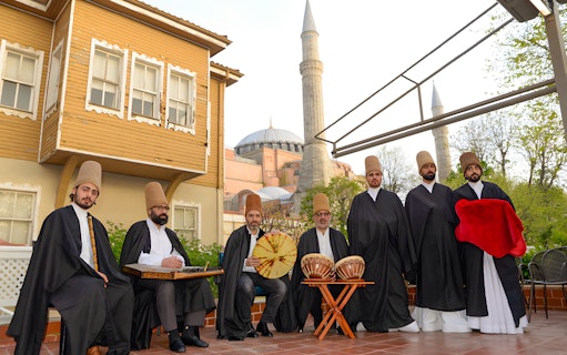 Whirling dervishes in traditional attire with Hagia Sophia in the background, Istanbul.