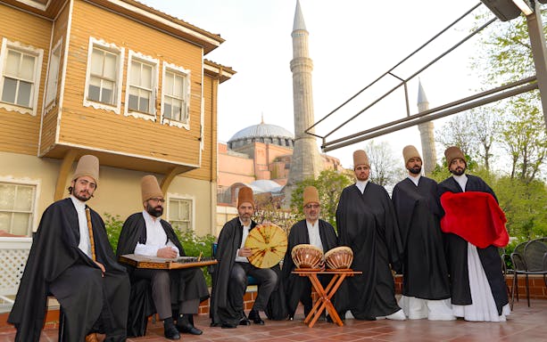 Whirling dervishes in traditional attire with Hagia Sophia in the background, Istanbul.