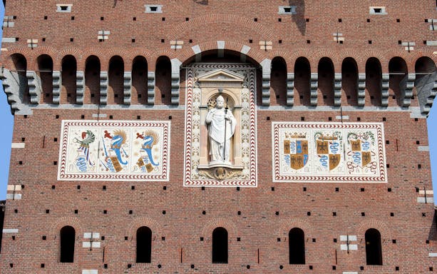 Sforza Castle battlements with detailed frescoes and statue, Milan, Italy.