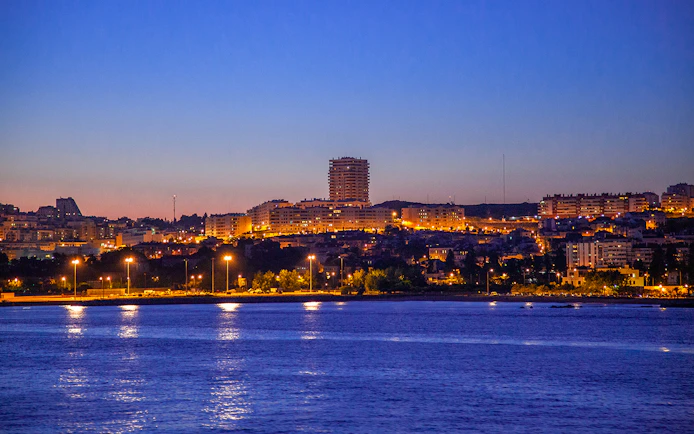 Lisbon cityscape at dusk viewed from a night cruise on the Tagus River.