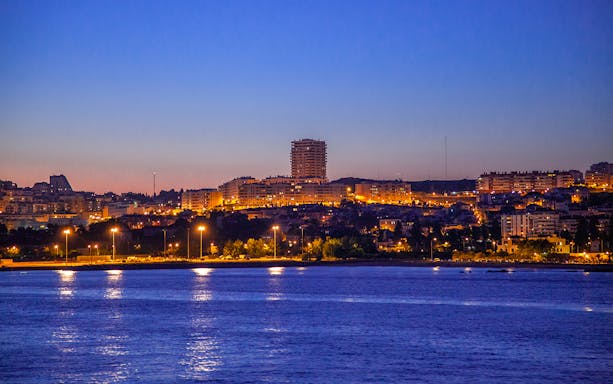 Lisbon cityscape at dusk viewed from a night cruise on the Tagus River.