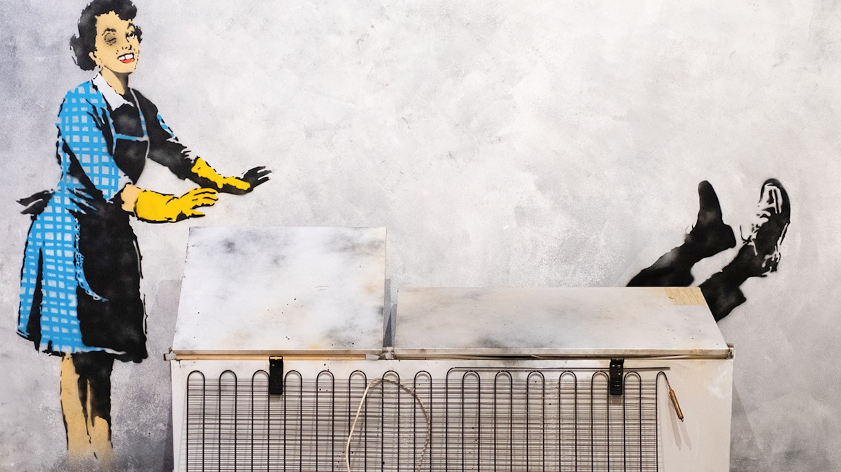 Street art of a woman pushing a man into a freezer at the Banksy Museum in Lisbon.