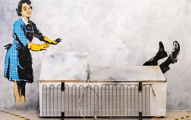 Street art of a woman pushing a man into a freezer at the Banksy Museum in Lisbon.