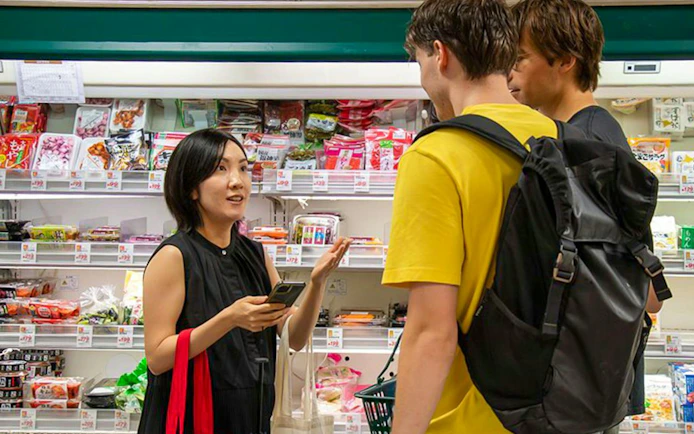 Participants shopping for ingredients in a Tokyo store during an izakaya-style cooking class.