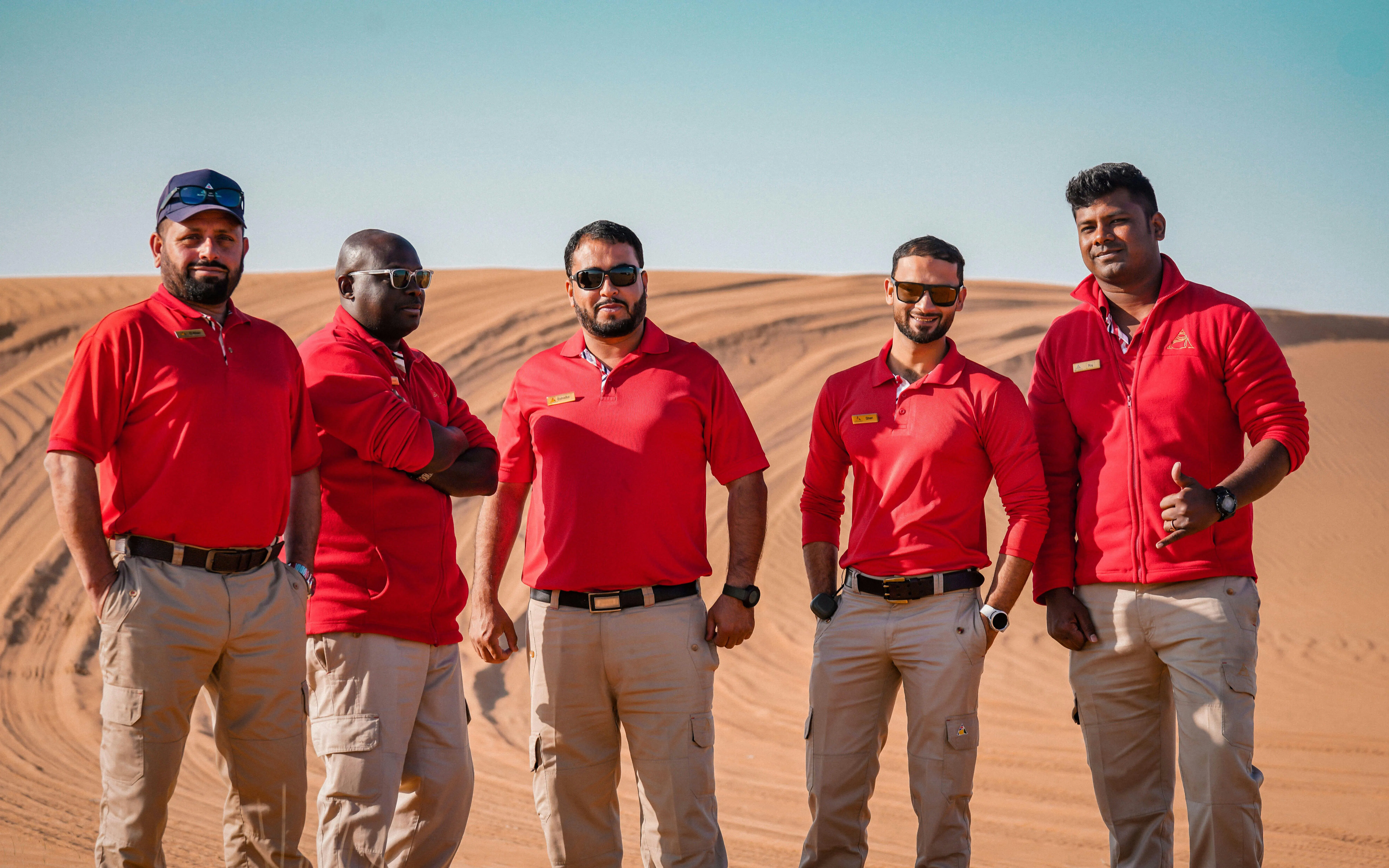 Dubai Desert Safari guides standing on sand dunes.