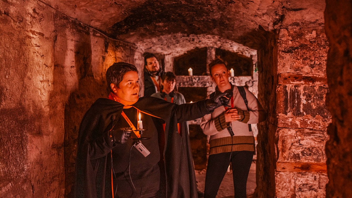 Guests with guide holding candle on Ghostly Underground tour in Edinburgh.