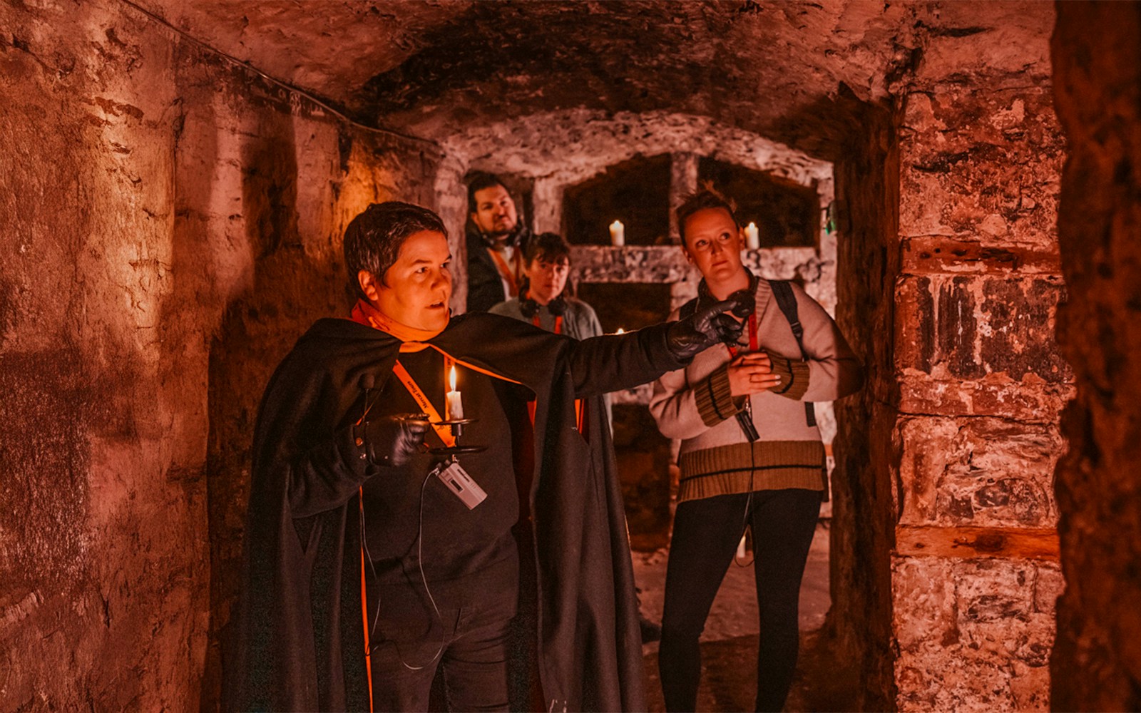 Guests with guide holding candle on Ghostly Underground tour in Edinburgh.