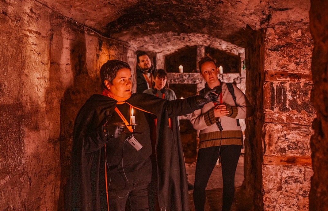 Guests with guide holding candle on Ghostly Underground tour in Edinburgh.