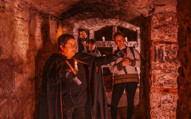 Guests with guide holding candle on Ghostly Underground tour in Edinburgh.
