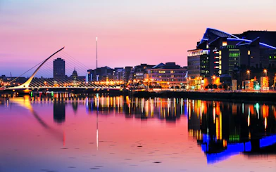 Samuel Beckett Bridge and Dublin skyline at sunset, reflecting on the River Liffey.
