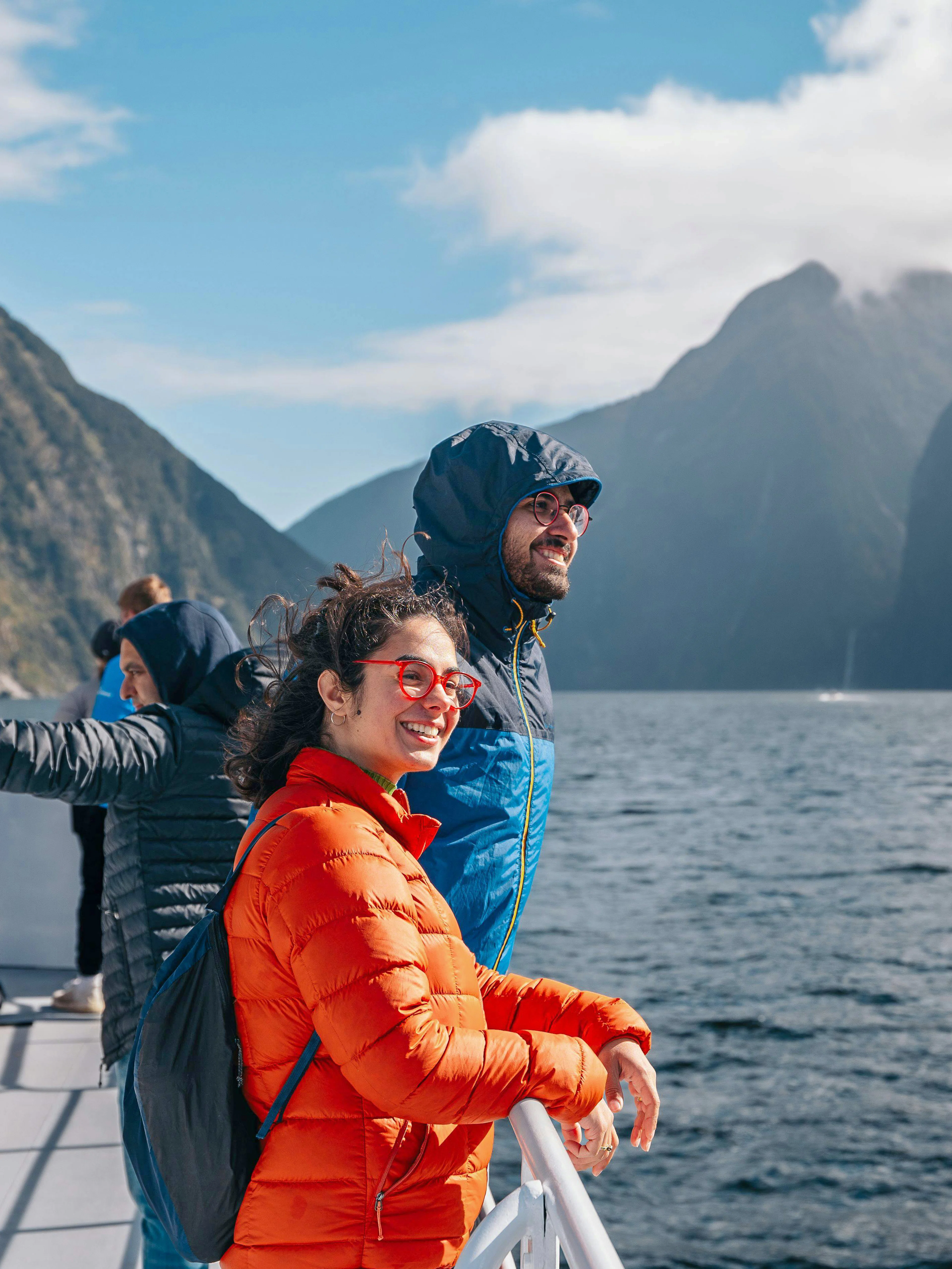 Tourists enjoying a scenic cruise on Milford Sound with mountains in the background.