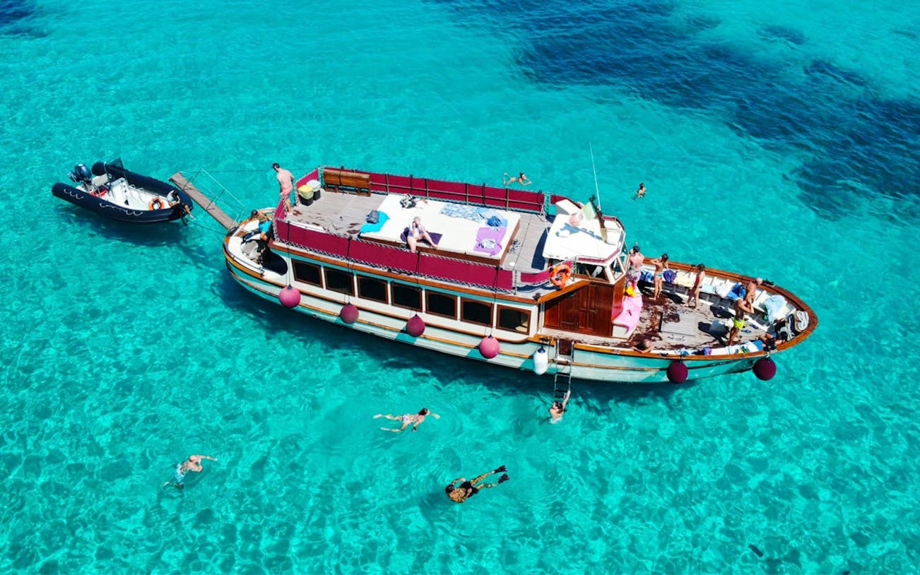 Motorboat with tourists swimming in clear waters of La Maddalena Archipelago.
