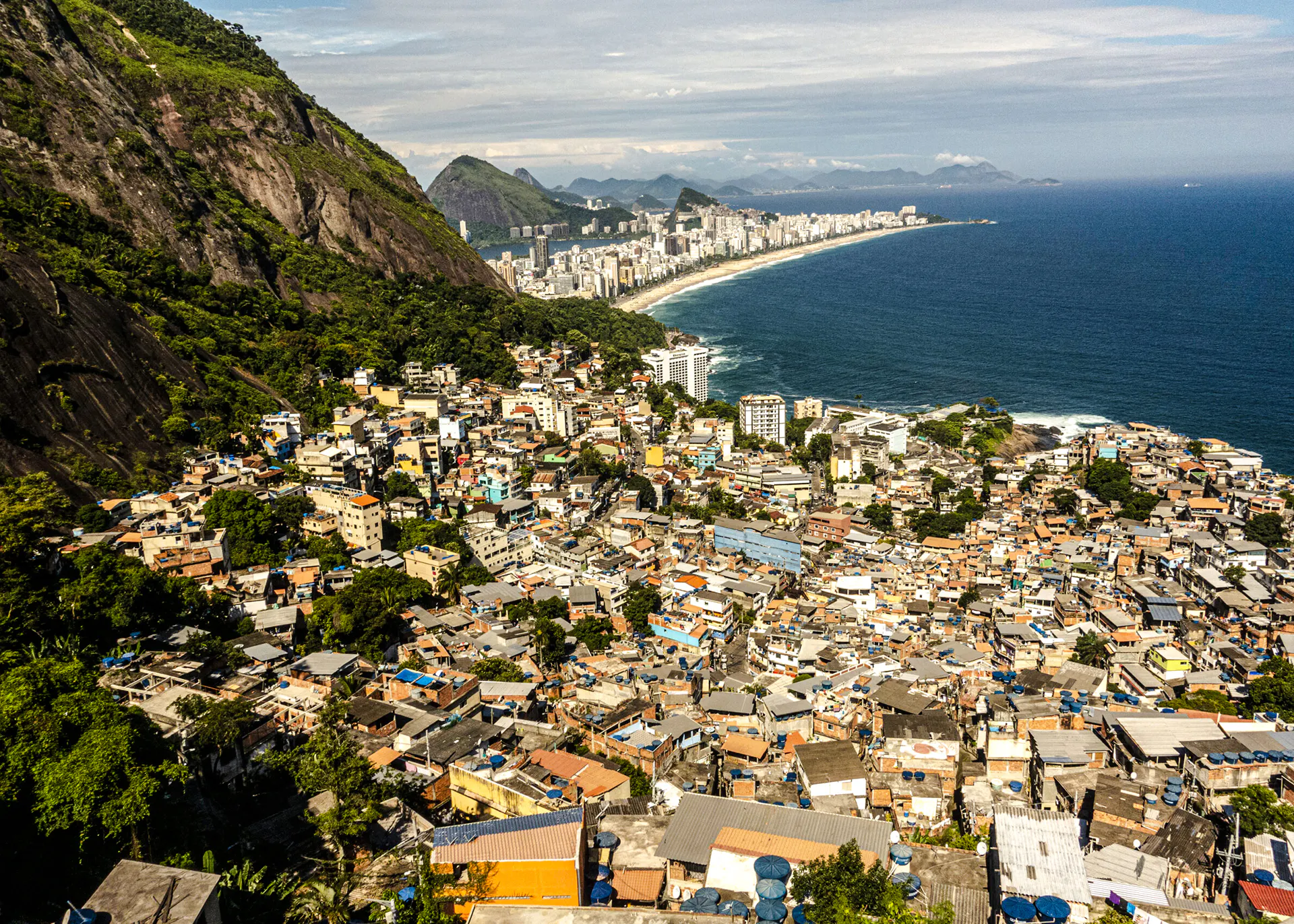 Aerial view of Vidigal favela with Rio de Janeiro coastline and ocean in the background.