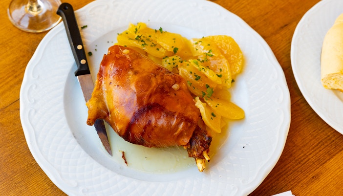 Pork meat with roasted potatoes on a white plate.