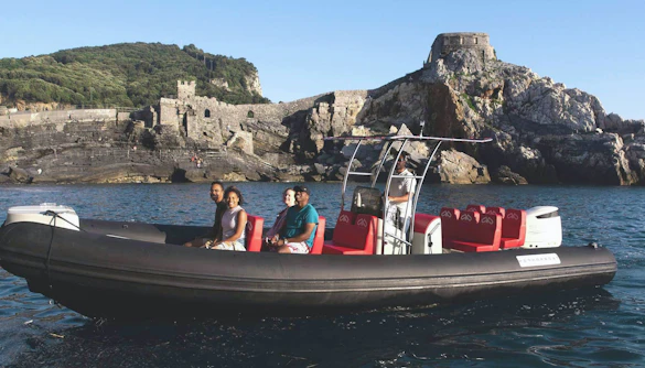 Boat with tourists near Portovenere's rocky coastline, La Spezia.