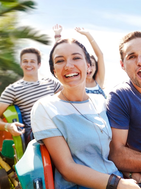 People enjoying a rollercoaster ride with palm trees in the background.