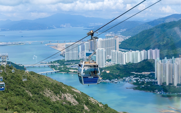 Cable car over Hong Kong landscape with city and water views.
